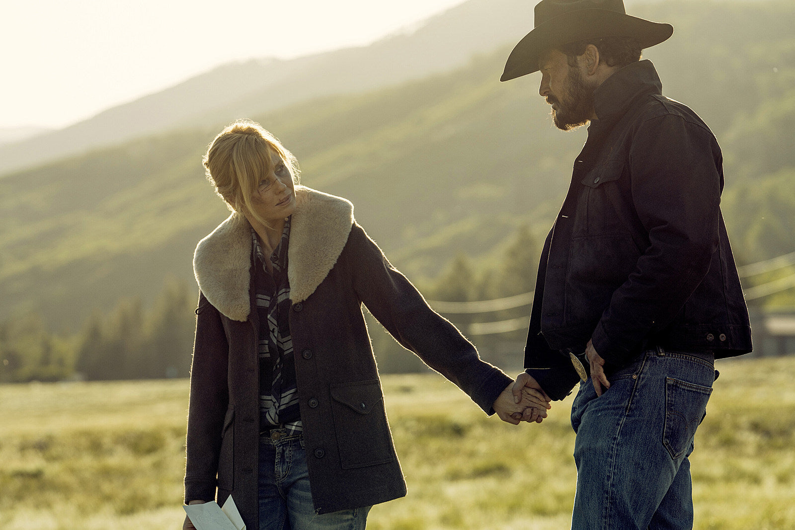 Two people holding hands in a scenic outdoor setting Yellowstone beth dutton brown wool coat Rip Wheeler