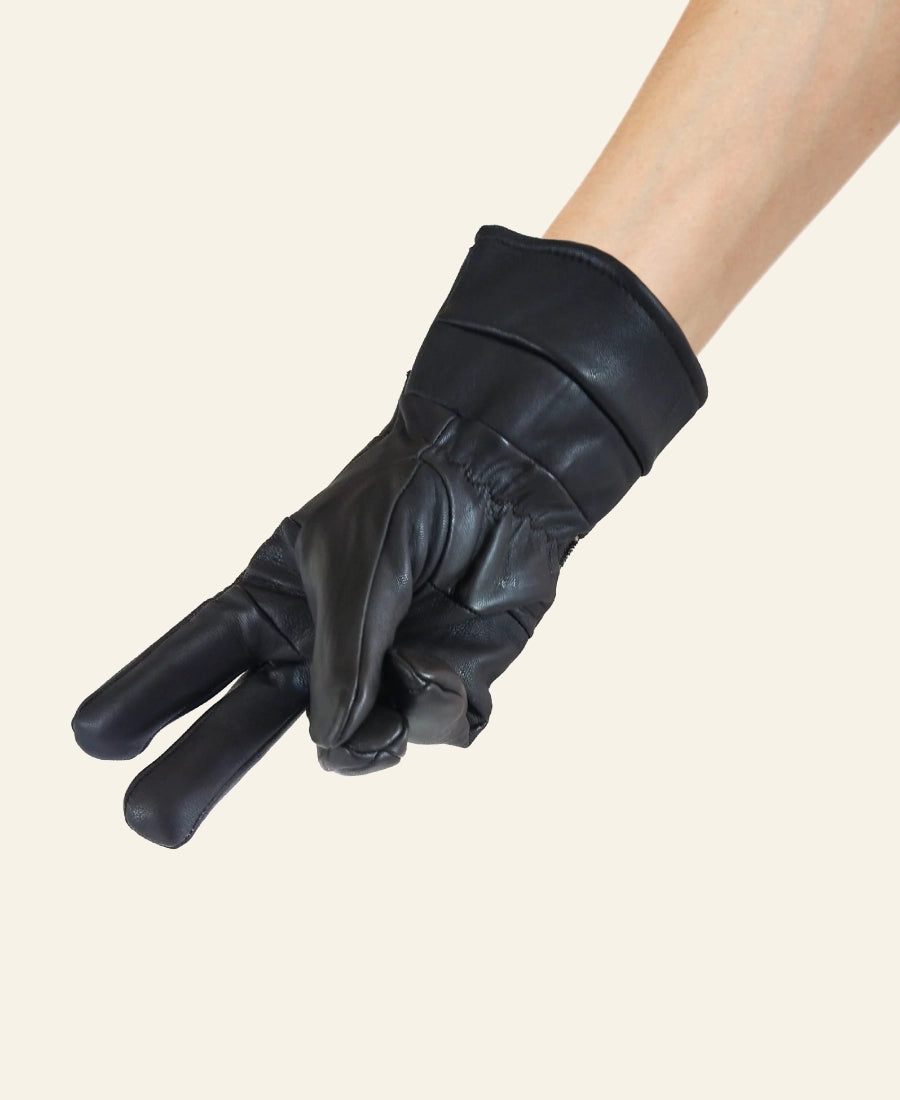 Black leather Rip Wheeler glove on a beige background