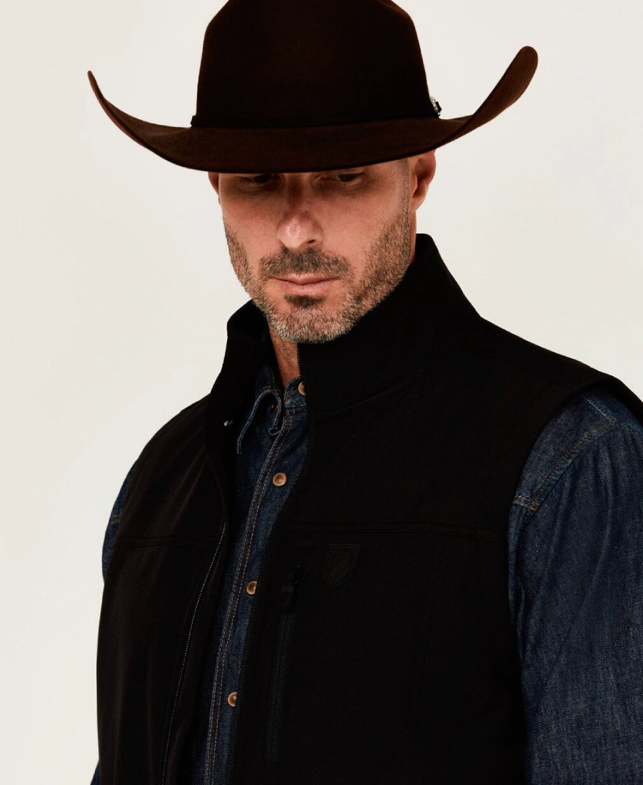 Man wearing a Rip Wheeler black wool vest with cowboy hat and dark clothing on a white background