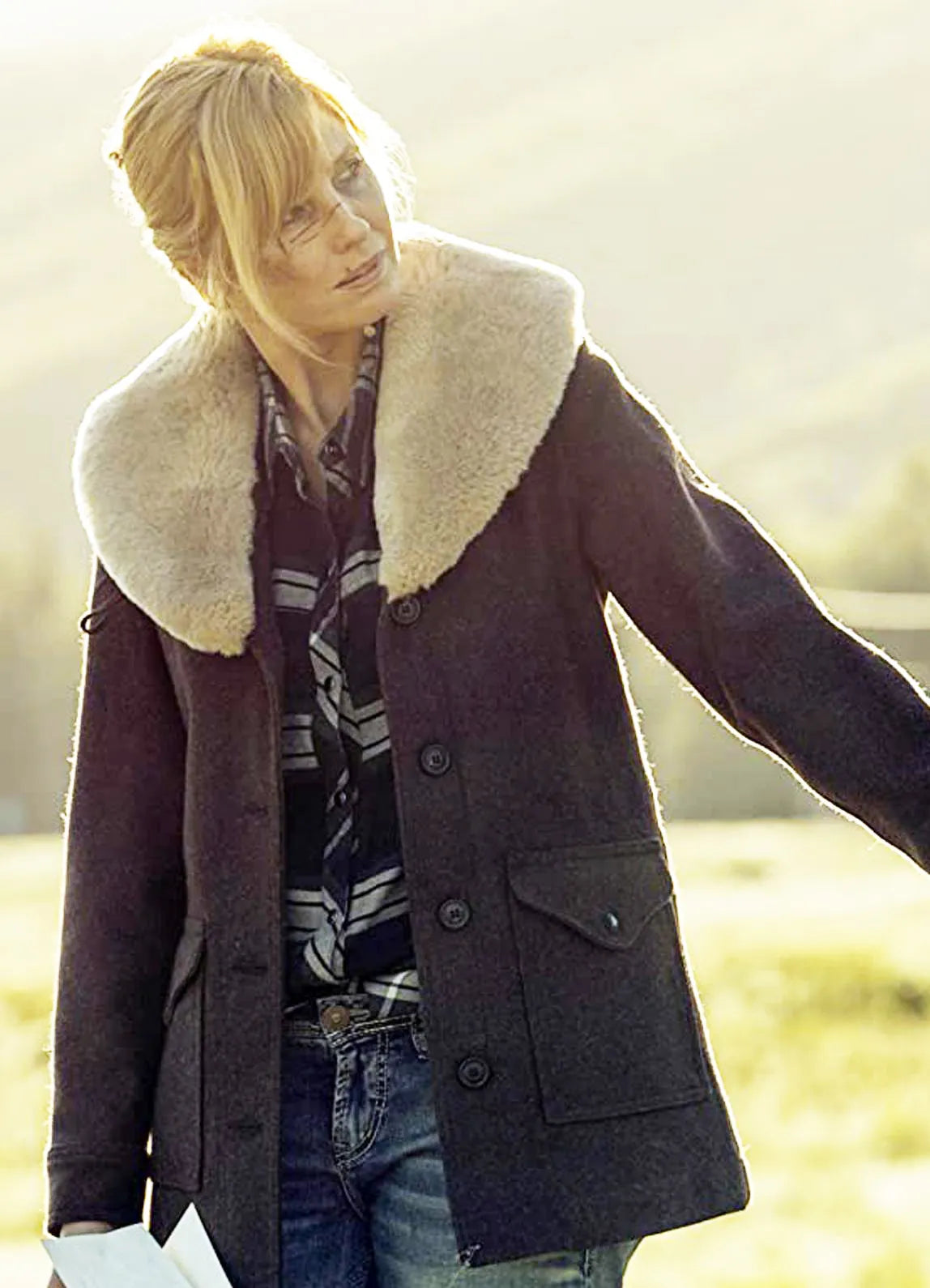 Beth Dutton wearing a dark coat with a light fur collar in an outdoor