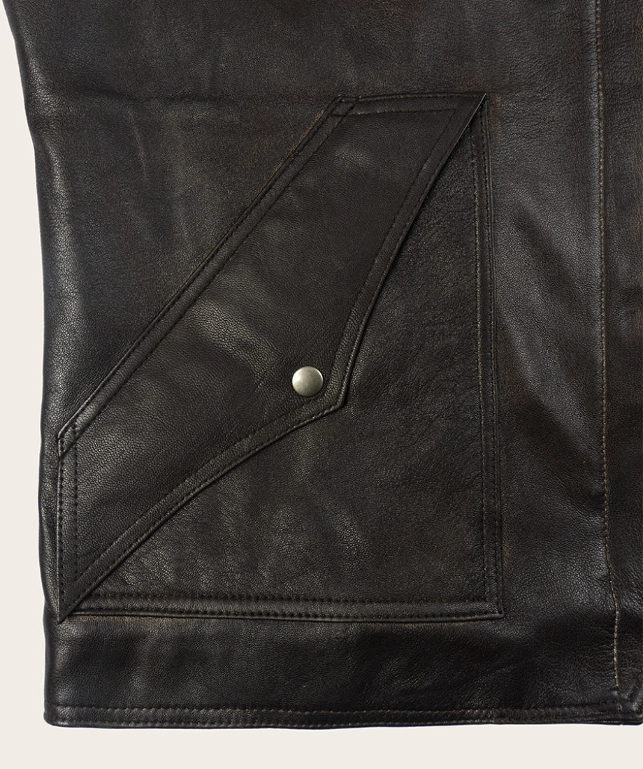 Close-up of a black leather jacket with a button on a beige background
