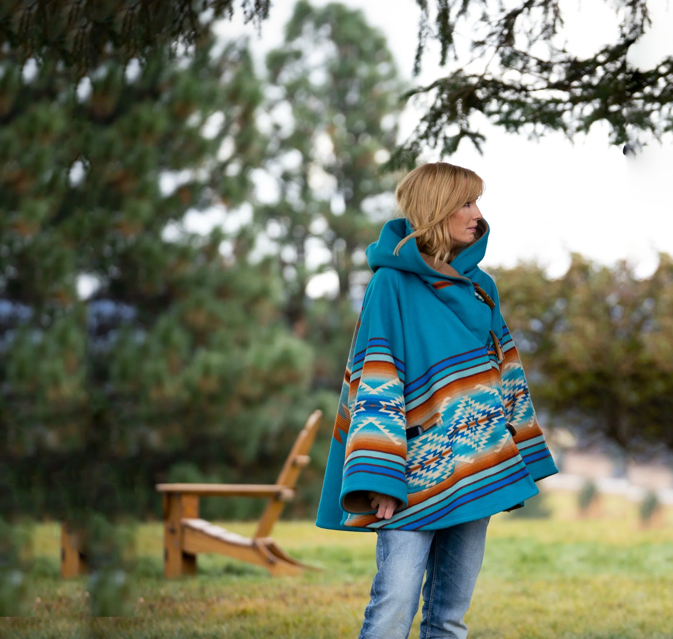 Yellowstone Beth Dutton Person wearing a blue patterned coat standing outdoors with trees in the background
