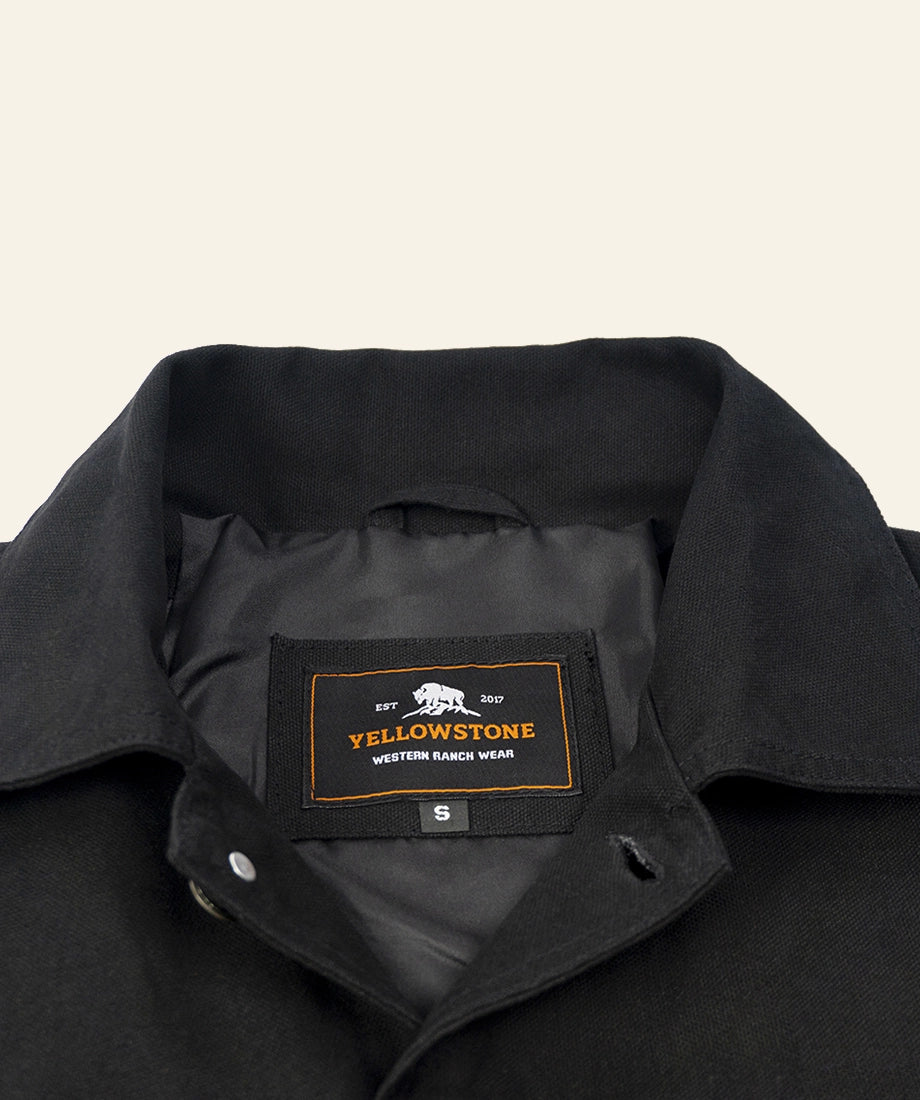 Close-up of a black jacket with a Yellowstone label on a beige background