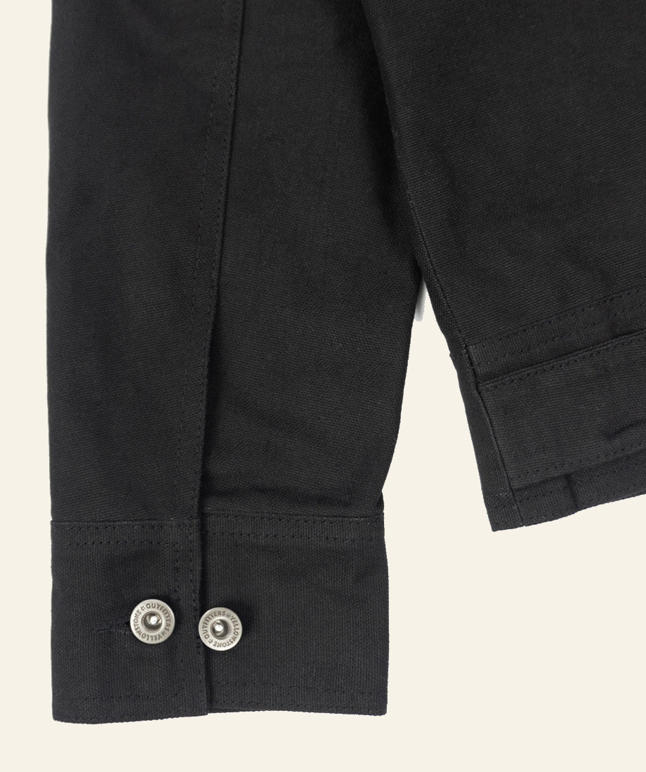 Close-up of a black jacket with buttons on a beige background