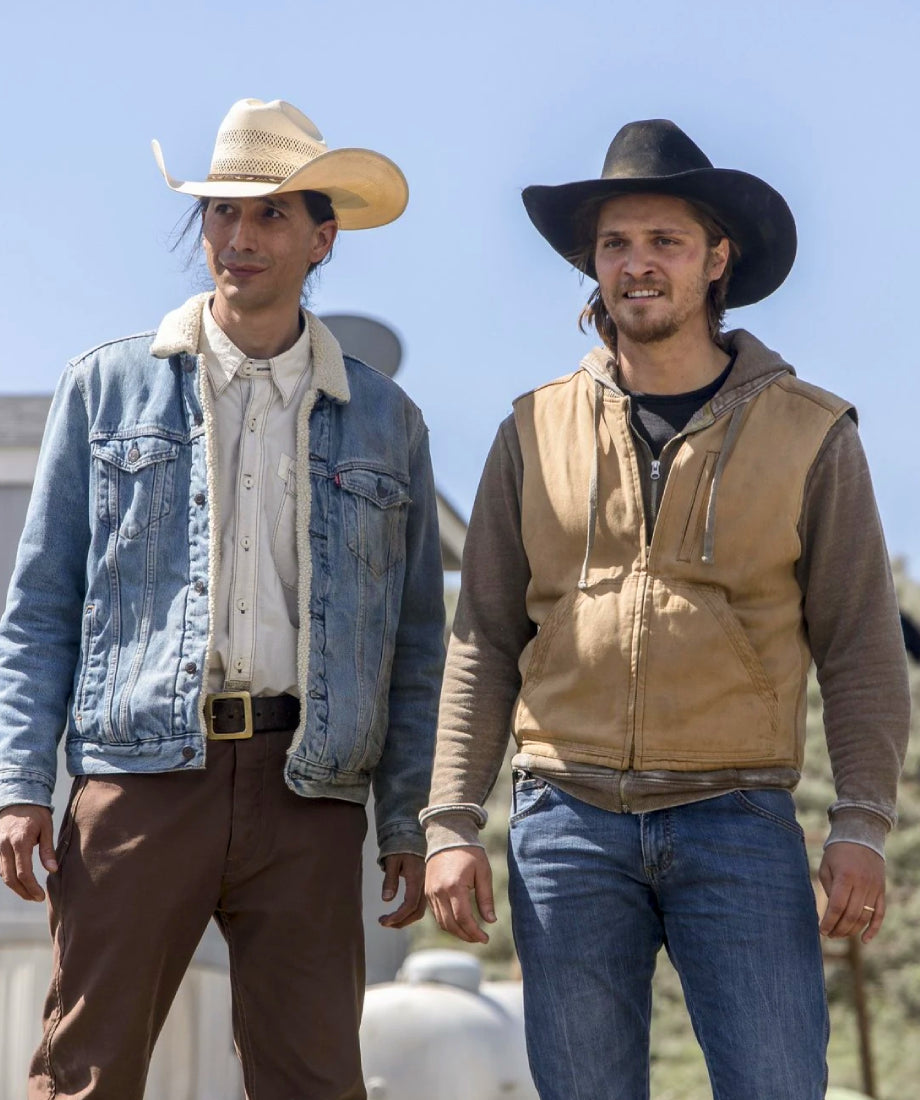 Two men wearing cowboy hats and casual attire standing outdoors with a clear blue sky.