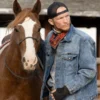 Jimmy Hurdstrom denim jacket standing next to a brown horse with a white stripe on its face.
