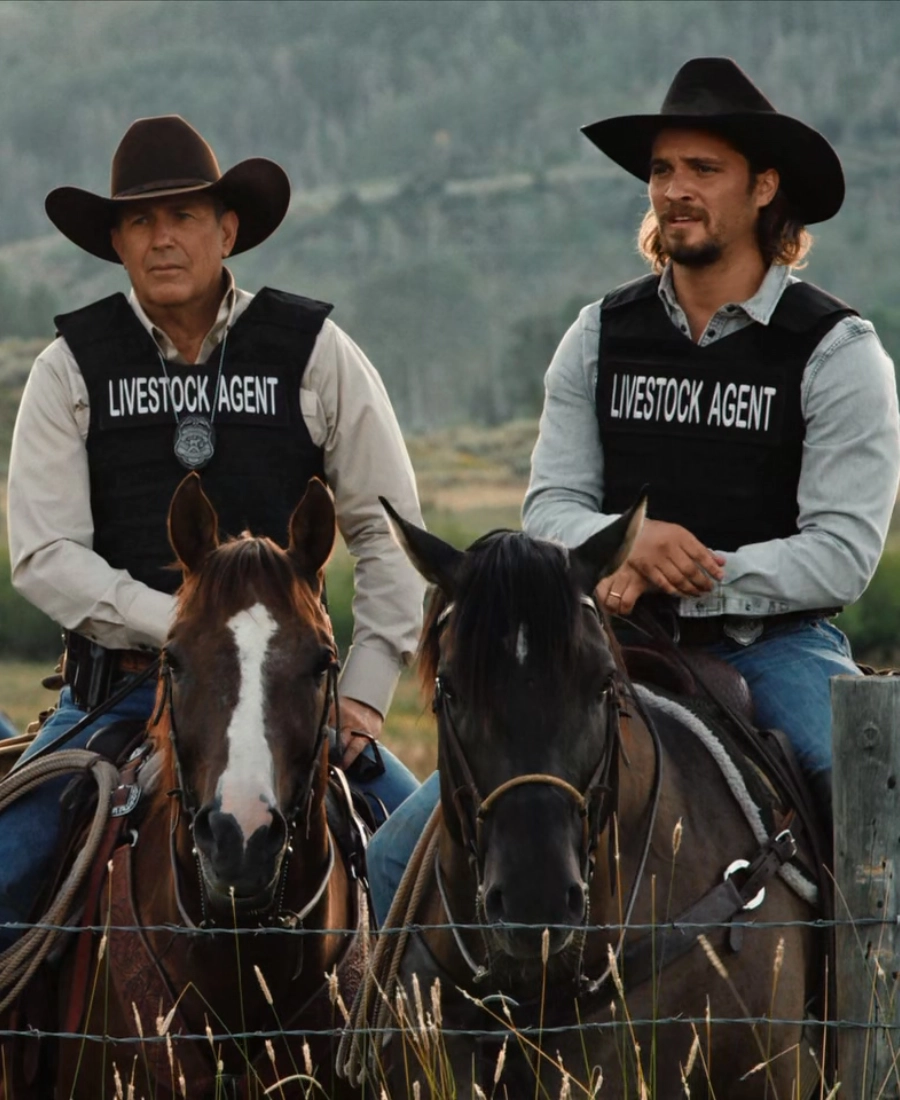Yellowstone TV Series Two men in livestock agent vests sitting on horses in a field.