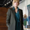 Beth Dutton wearing a gray coat over a teal shirt in an indoor setting